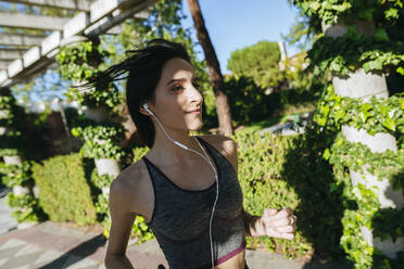 Frau mit Kopfhörern, die im Freien läuft - KIJF02711