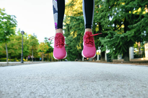 Nahaufnahme der Füße einer Frau mit rosa Laufschuhen beim Springen - KIJF02727
