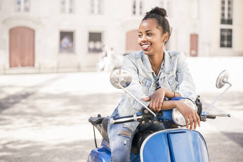 Happy young woman with motor scooter in the city, Lisbon, Portugal stock photo