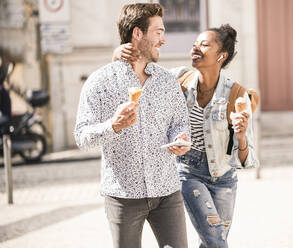 Happy young couple with ice cream and mobile phone in the city on the go, Lisbon, Portugal - UUF19217