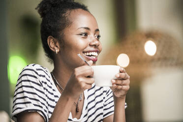 Porträt einer glücklichen jungen Frau mit einer Kaffeetasse in einem Cafe - UUF19223