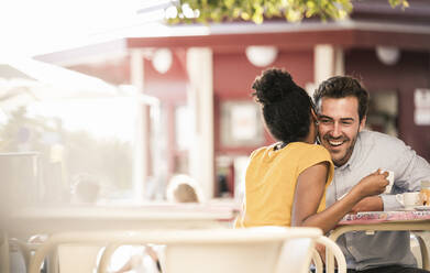 Happy young couple socializing at an outdoor cafe - UUF19246