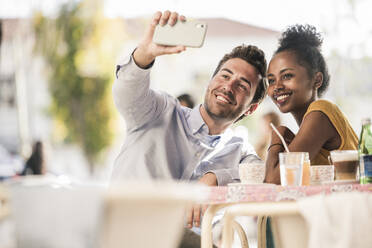 Glückliches junges Paar macht ein Selfie in einem Straßencafé - UUF19249