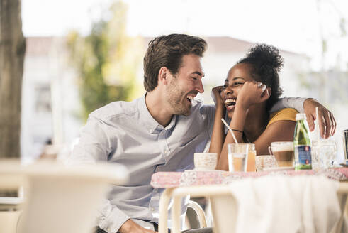 Lachendes junges Paar in einem Straßencafé - UUF19250
