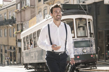 Smiling young businessman in the old town on the go, Lisbon, Portugal - UUF19251