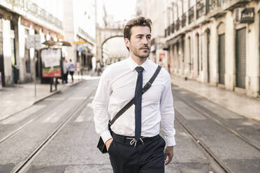 Confident young businessman in the city on the go, Lisbon, Portugal - UUF19253