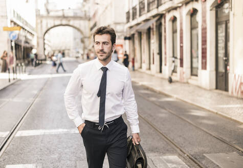 Confident young businessman in the city on the go, Lisbon, Portugal - UUF19254