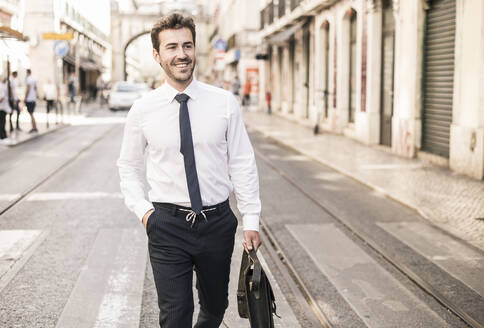 Smiling young businessman in the city on the go, Lisbon, Portugal - UUF19255