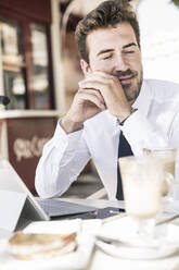 Young businessman having a break at a cafe in the city, Lisbon, Portugal - UUF19267