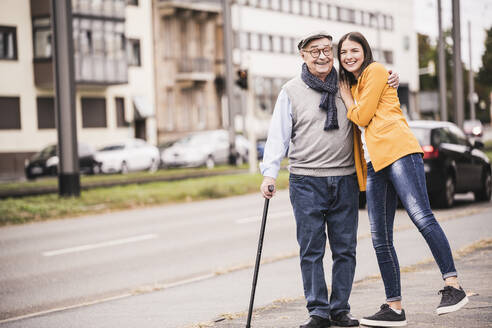 Portrait of happy senior man strolling with his adult granddaughter - UUF19279