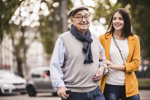 Portrait of senior man strolling together with his adult granddaughter - UUF19282