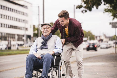 Junger Mann schiebt glücklichen älteren Mann im Rollstuhl - UUF19287