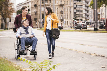 Senior man in wheelchair spending time with his grandchildren - UUF19294