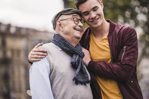 Happy senior man head to head with his adult grandson outdoors - UUF19310