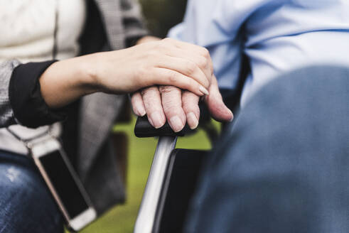 Young woman touching senior man's hand, close-up - UUF19320