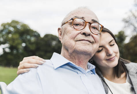 Porträt eines selbstbewussten älteren Mannes mit seiner Enkelin in einem Park - UUF19325