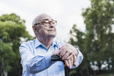 Porträt eines älteren Mannes in einem Park, der sich auf seinen Spazierstock stützt - UUF19331