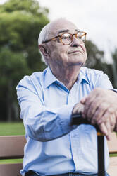 Porträt eines älteren Mannes in einem Park, der sich auf seinen Spazierstock stützt - UUF19333