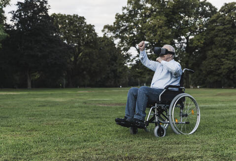 Senior man sitting in wheelchair using Virtual Reality Glasses - UUF19352