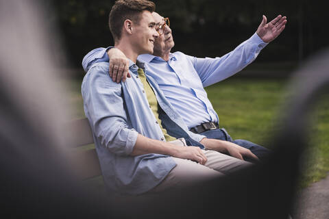 Senior man and grandson relaxing together on a park bench stock photo