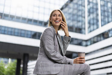 Happy young businesswoman on the phone in the city - DIGF08653