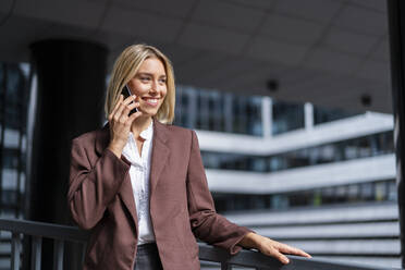 Smiling young businesswoman on the phone in the city - DIGF08683