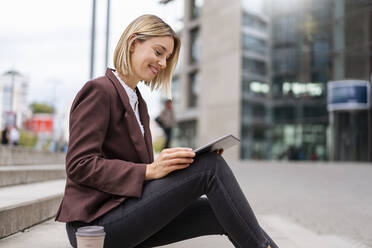 Smiling young businesswoman using tablet in the city - DIGF08693