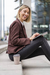 Portrait of happy young businesswoman using tablet in the city - DIGF08694
