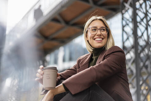 Glückliche junge Geschäftsfrau mit Kaffee zum Mitnehmen in der Stadt - DIGF08714