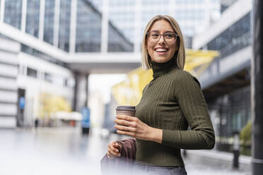 Glückliche junge Frau mit Kaffee zum Mitnehmen in der Stadt - DIGF08716