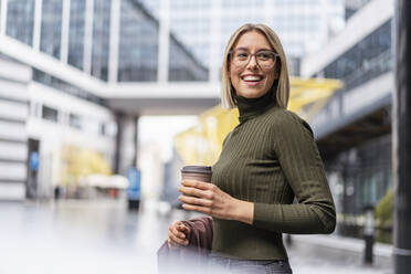 Happy young woman with takeaway coffee in the city - DIGF08716