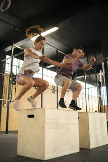Young couple doing box jump exercise during cross training - MTBF00069