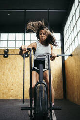 Sportliche Frau beim Airbike-Training im Fitnessstudio - MTBF00079