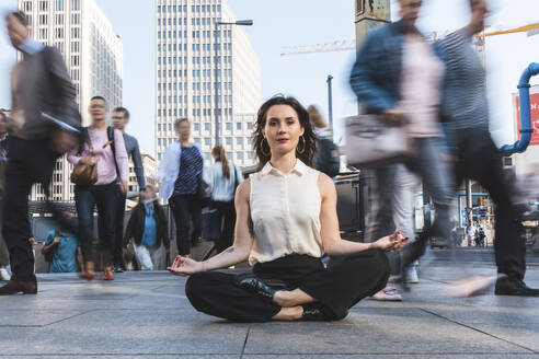 Young businesswoman practising yoga in the city at rush hour, Berlin, Germany - WPEF02183
