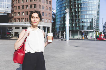 Junge Geschäftsfrau mit Kaffee zum Mitnehmen in der Stadt unterwegs, Berlin, Deutschland - WPEF02184