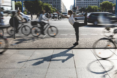 Junge Geschäftsfrau übt Yoga in der Stadt zur Hauptverkehrszeit, Berlin, Deutschland, lizenzfreies Stockfoto