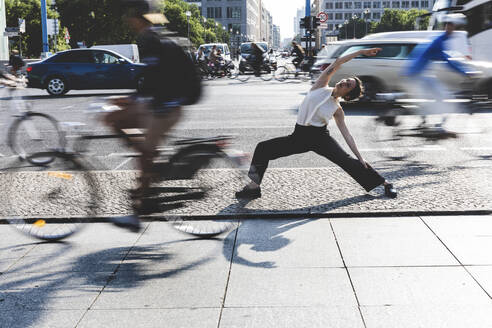 Young businesswoman practising yoga in the city at rush hour, Berlin, Germany - WPEF02190