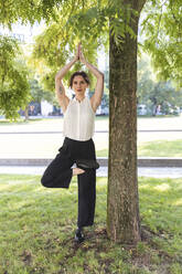 Junge Geschäftsfrau übt Yoga in einem Park - WPEF02197