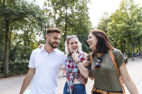 Gruppe von drei Freunden, die zusammen in einem Park spazieren gehen und Spaß haben, lizenzfreies Stockfoto