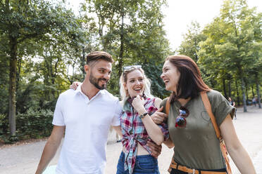 Gruppe von drei Freunden, die zusammen in einem Park spazieren gehen und Spaß haben - WPEF02218