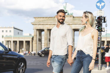 Glückliches junges Paar geht Hand in Hand vor dem Brandenburger Tor, Berlin, Deutschland - WPEF02237