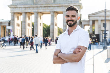 Porträt eines lächelnden jungen Mannes vor dem Brandenburger Tor, Berlin, Deutschland - WPEF02244