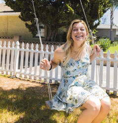 Happy woman swinging on swing at park - CAVF66664