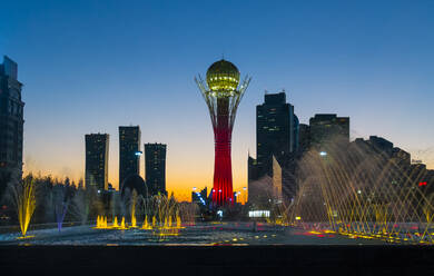 Illuminated Bayterek tower and fountain in city against clear blue sky - CAVF66671