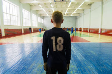 Rear view of player standing at indoor soccer court - CAVF66672