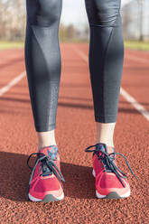 Low section of female athlete standing on sports track - CAVF66695