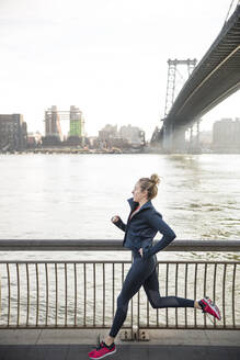 Seitenansicht eines Sportlers, der auf der Promenade am East River läuft - CAVF66701