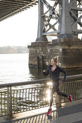 Selbstbewusster Sportler läuft auf der Promenade am East River - CAVF66702