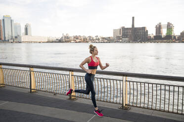 Weibliche Athletin läuft auf der Promenade am East River - CAVF66704