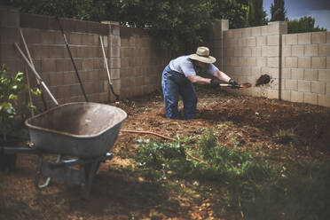 Man digging soil in backyard - CAVF66714